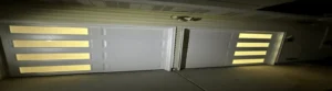 White garage doors with illuminated panels at night.